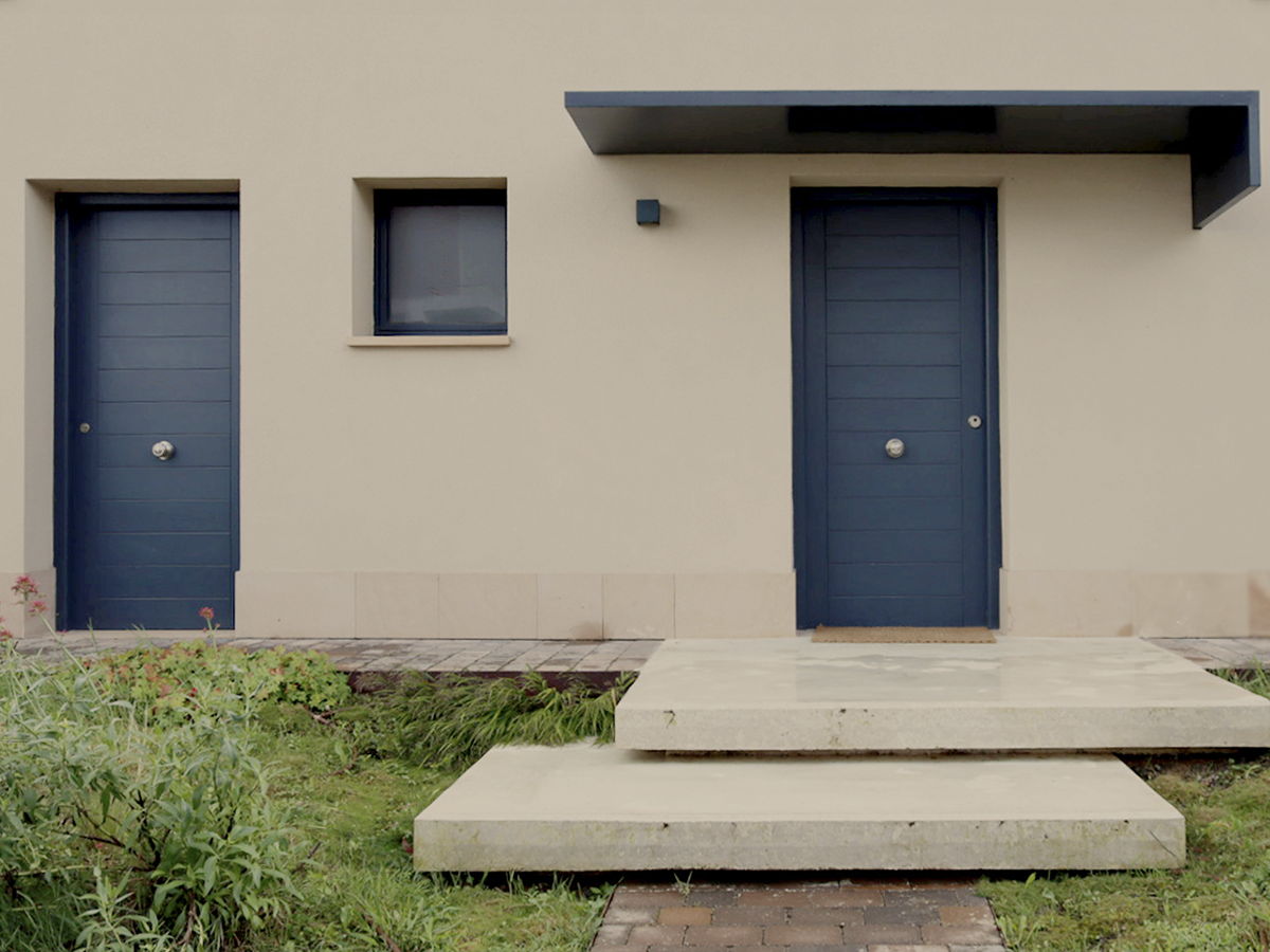 Fachada con puertas azules de vivienda en Luaña